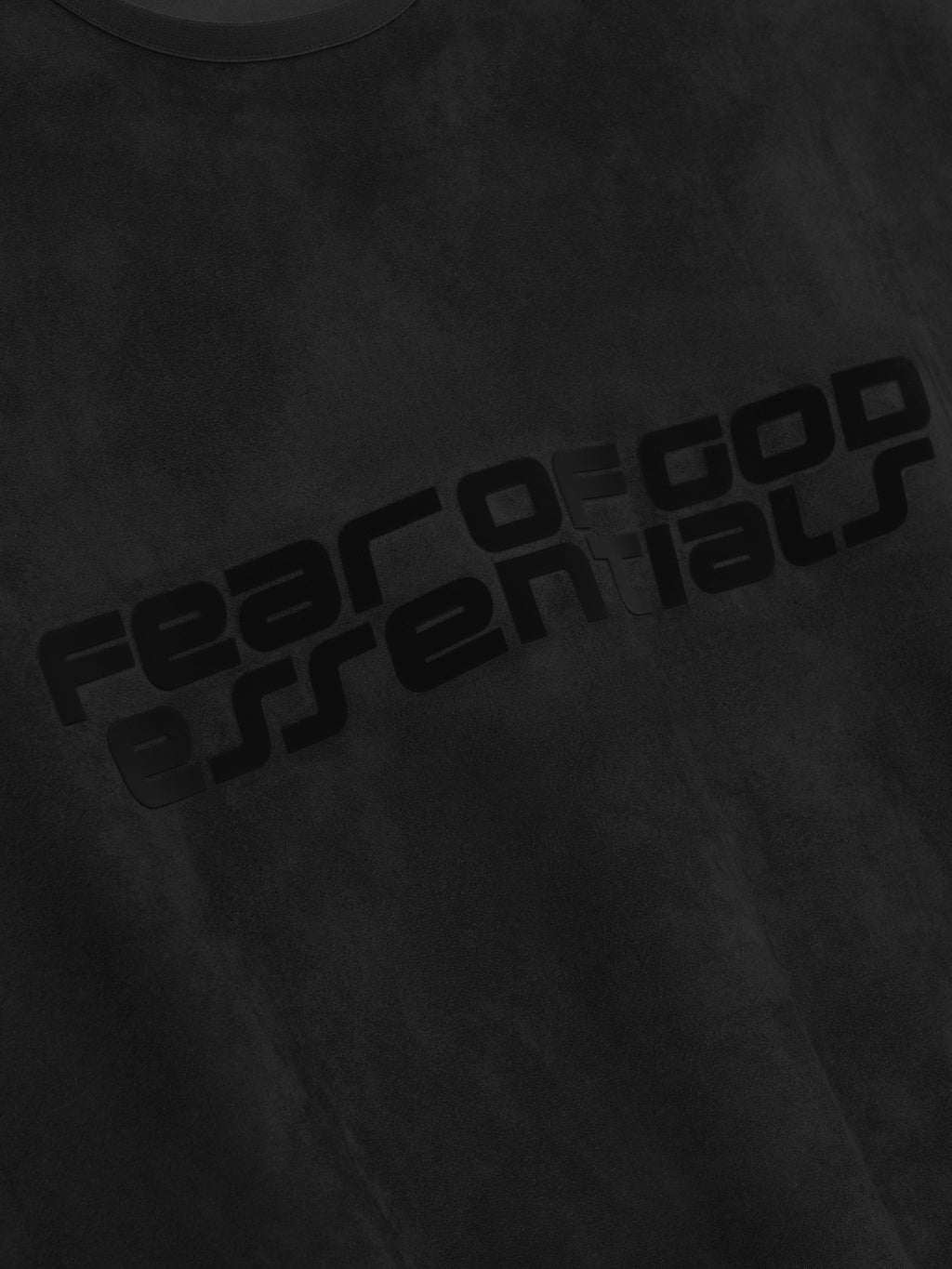 Close-up of vintage black modern crewneck sweatshirt with glossy black Fear of God Essentials logo printed diagonally across chest
