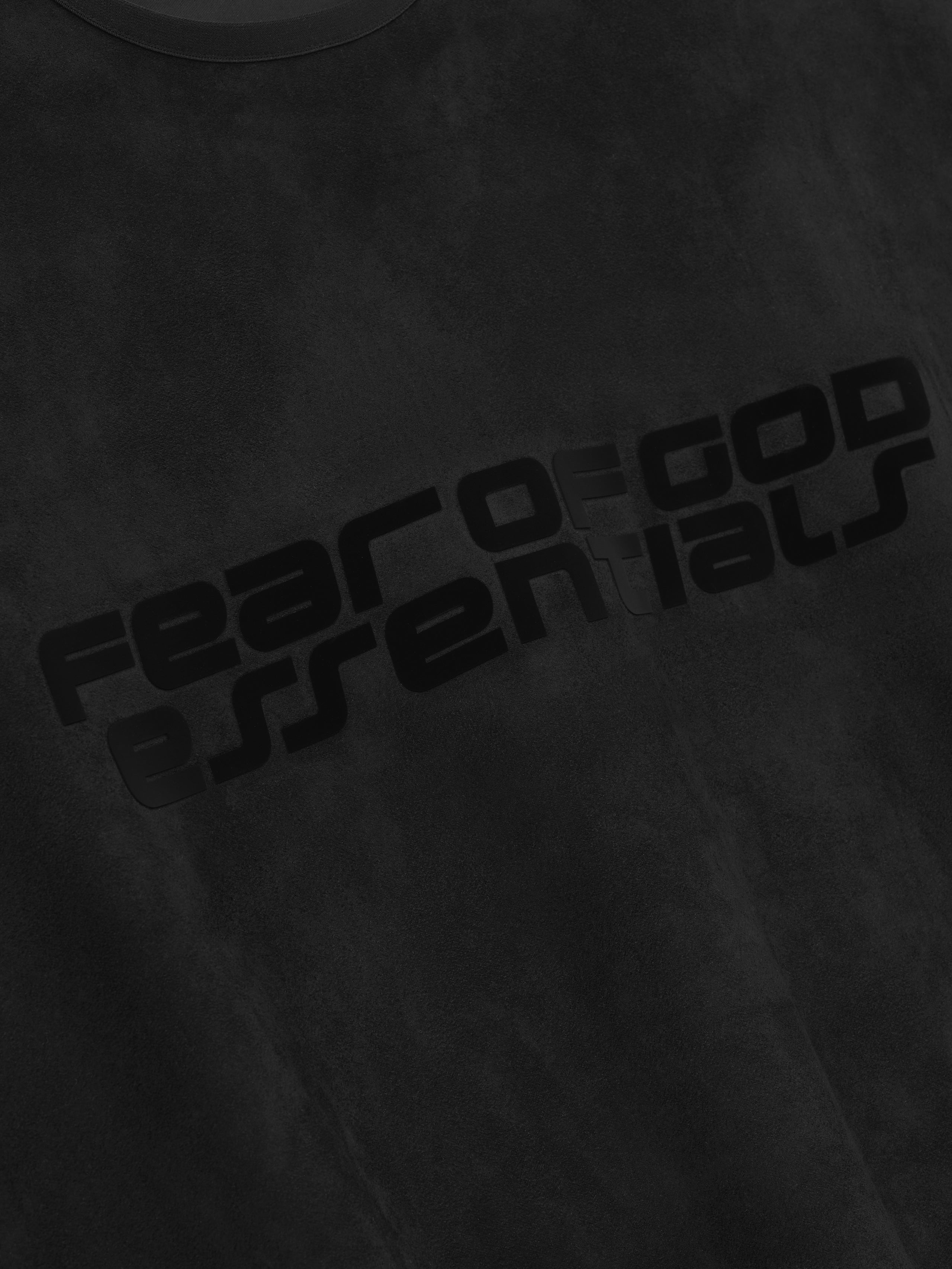 Close-up of vintage black modern crewneck sweatshirt with glossy black Fear of God Essentials logo printed diagonally across chest