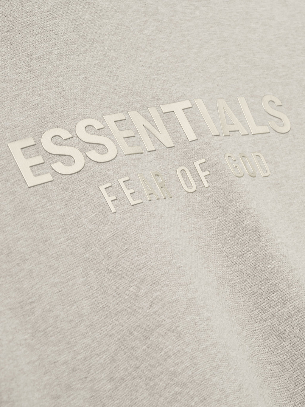 close-up of light beige fleece fabric with raised ESSENTIALS Fear of God logo printed in matching tone