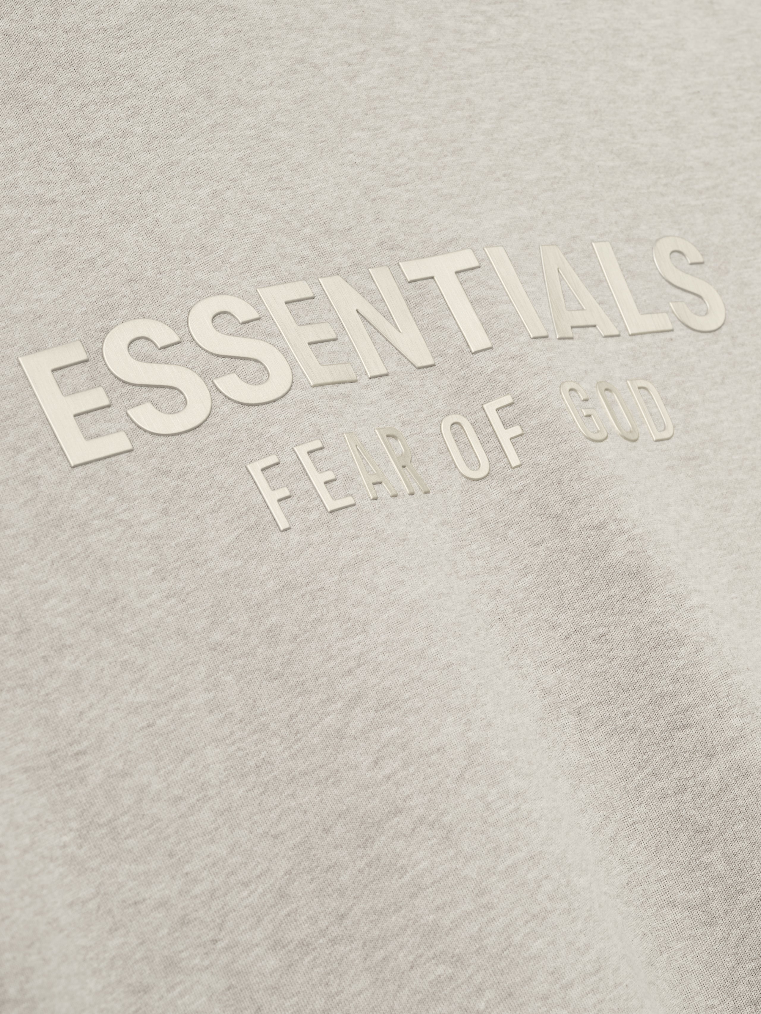 close-up of light beige fleece fabric with raised ESSENTIALS Fear of God logo printed in matching tone