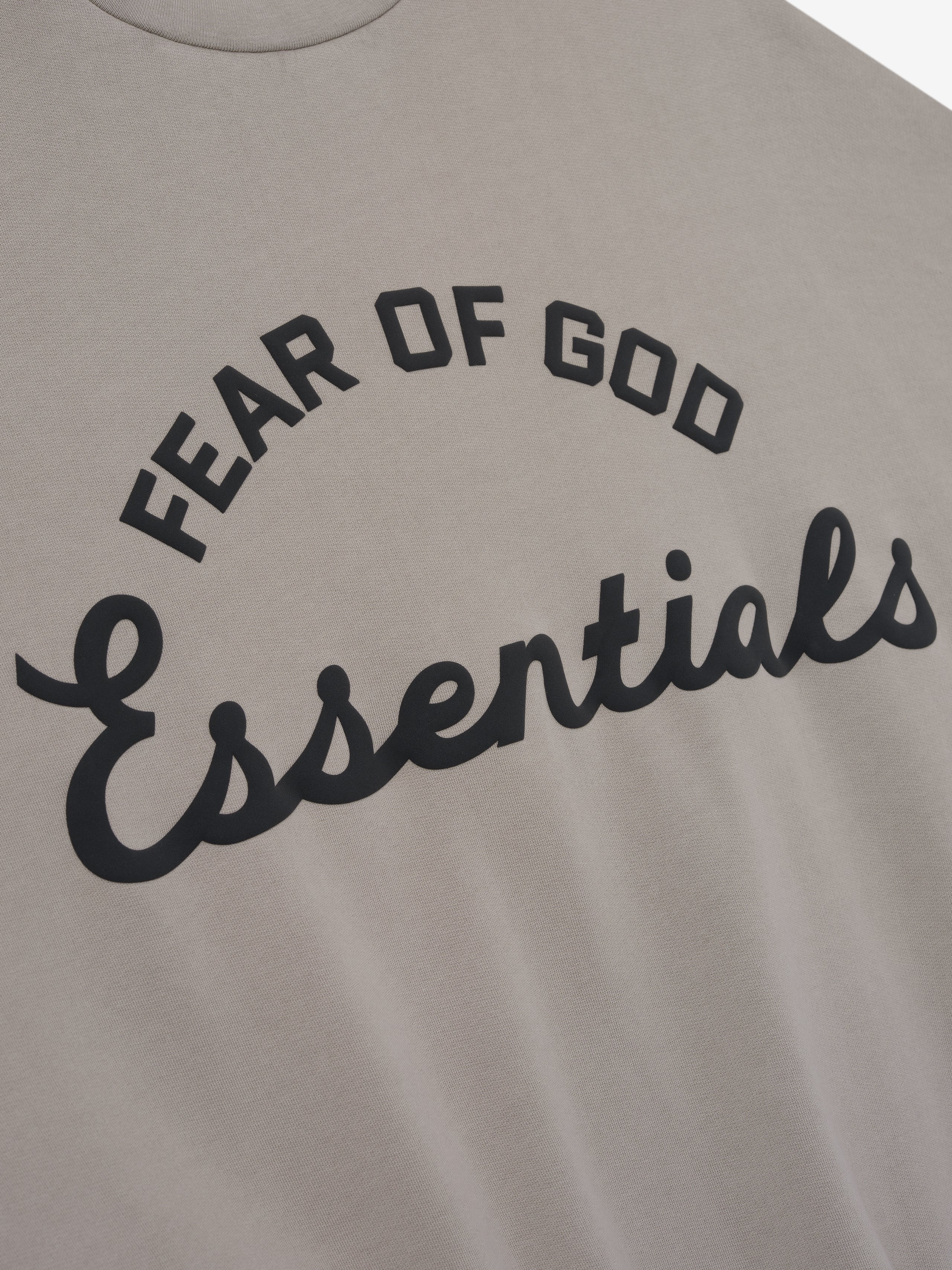 Gray sweatshirt with 'Fear of God Essentials' text on a plain background