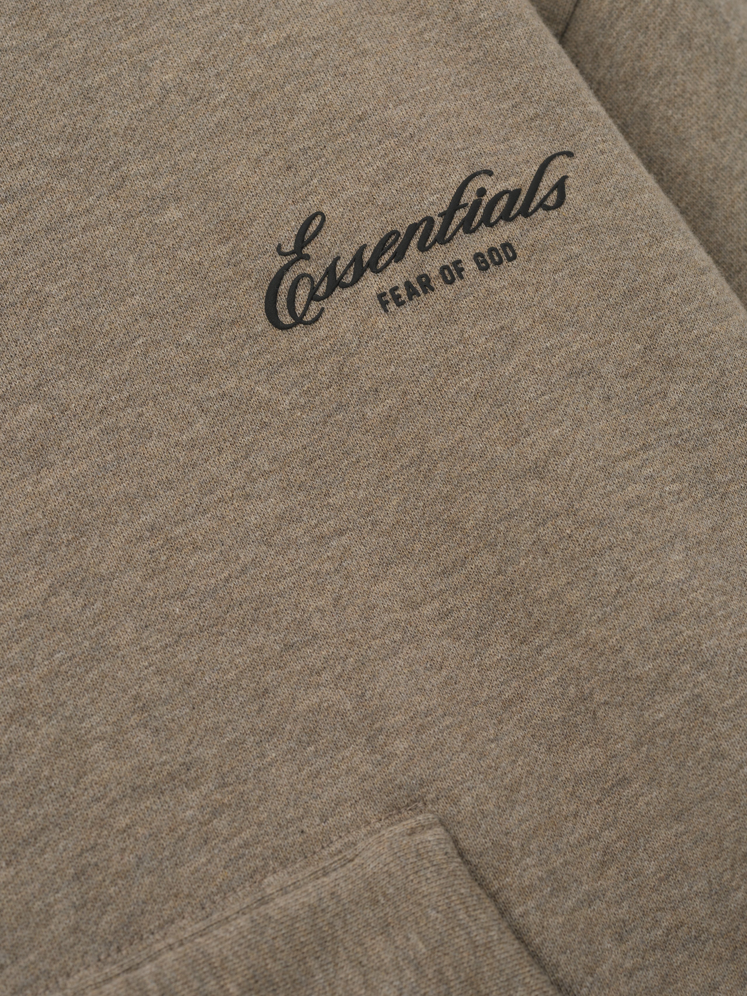 close-up of taupe core fleece fabric with black Essentials Fear of God logo printed on front chest panel