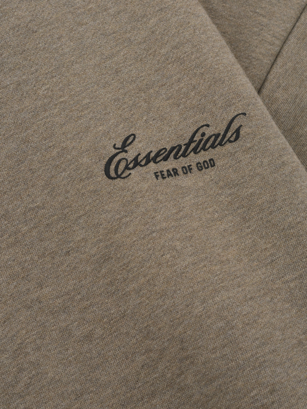 close-up of taupe core fleece fabric with Essentials Fear of God scripted logo printed on front chest panel