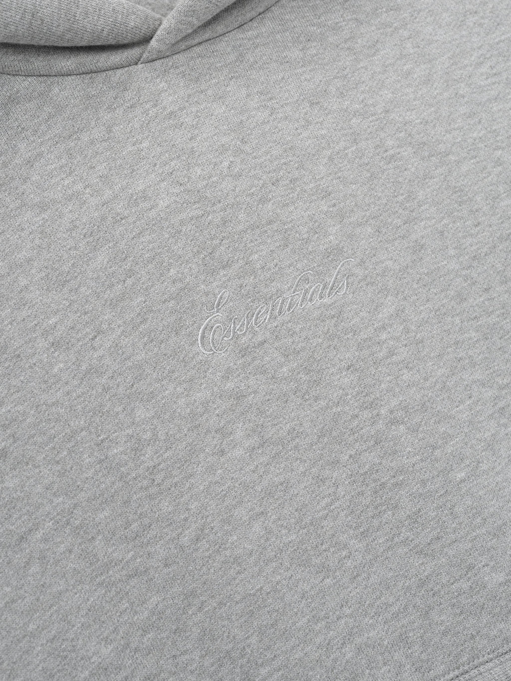 Close-up of a gray hoodie with essentials embroidery script