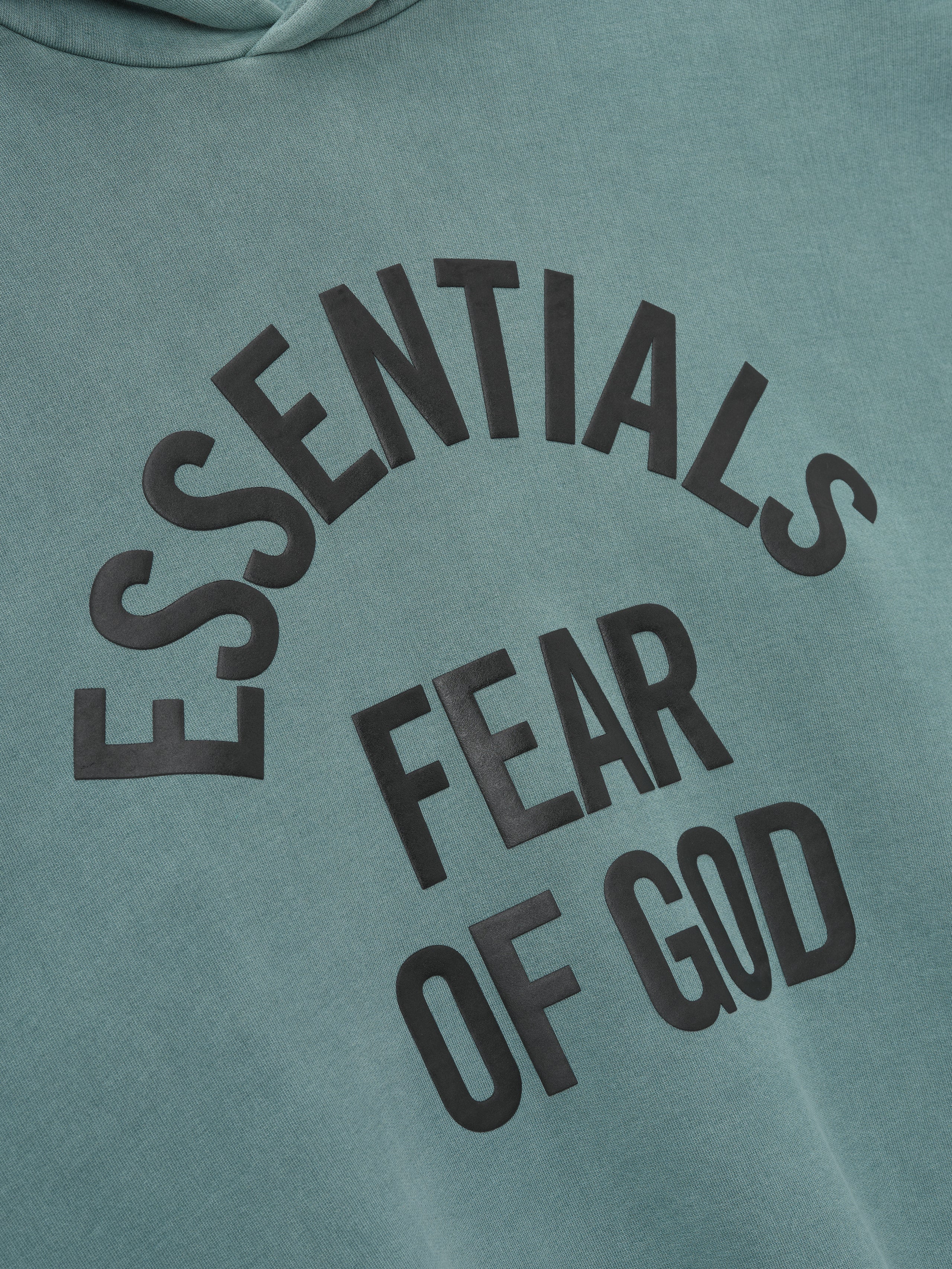 close-up of pigment-dyed green heavyweight fleece hoodie with large black Essentials Fear of God arched print on chest