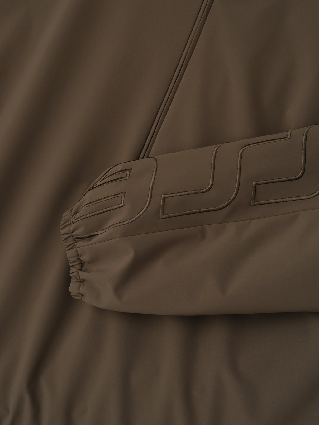 Close-up of a brown jacket with a brand logo on the chest.