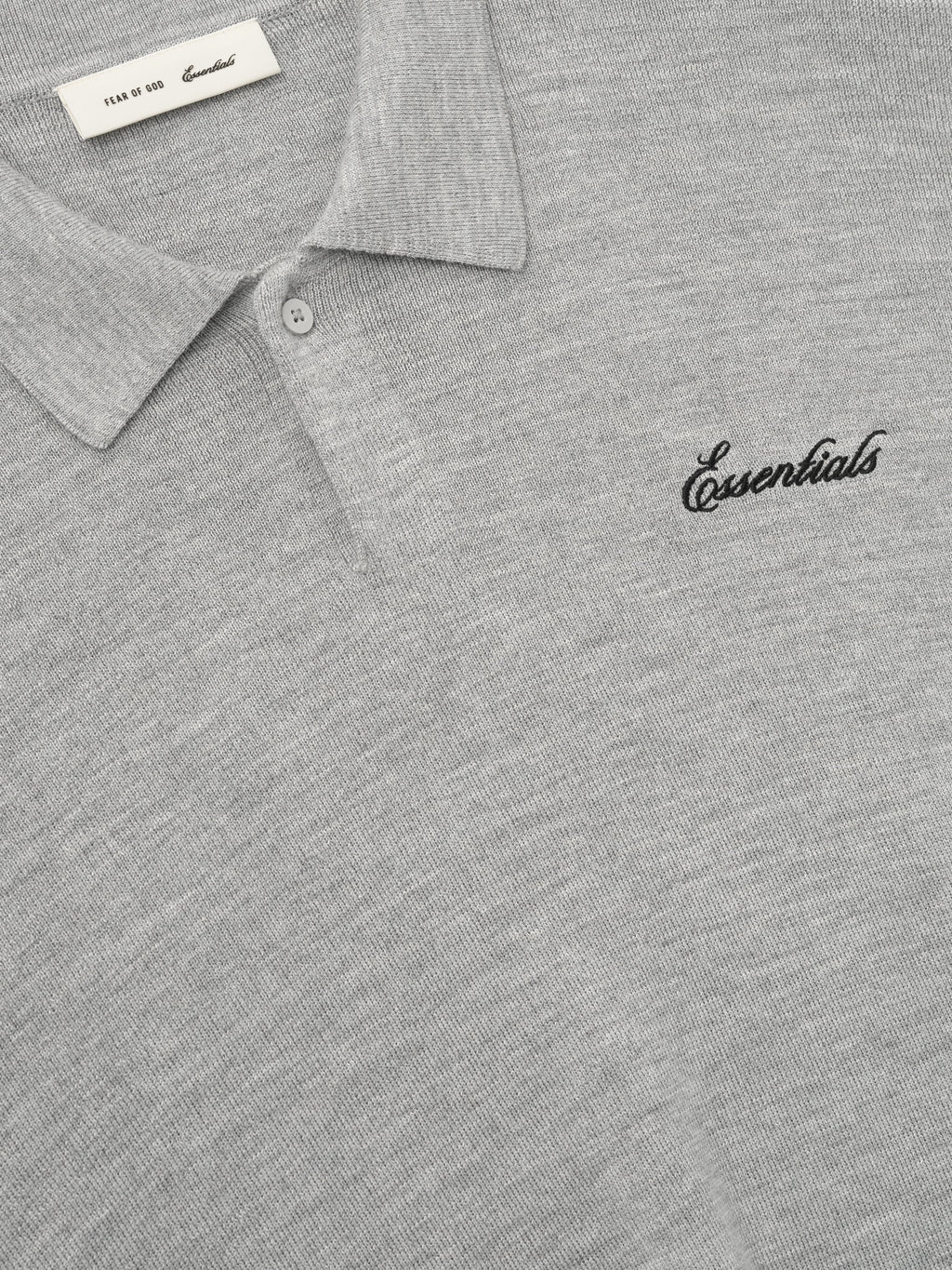 close-up of light grey heavy merino knit polo with classic collar and black Essentials script embroidery on chest
