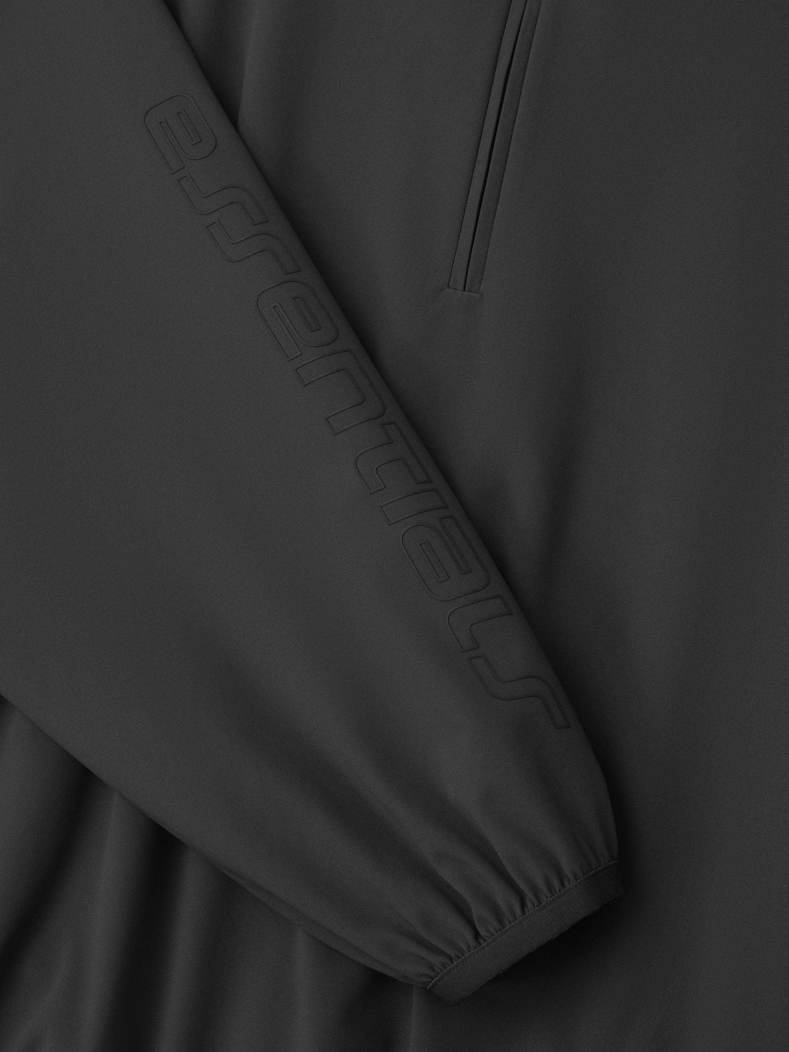 Close-up of womens iron grey nylon half zip track jacket sleeve with embossed Essentials logo and elastic cuff detail gallery 0