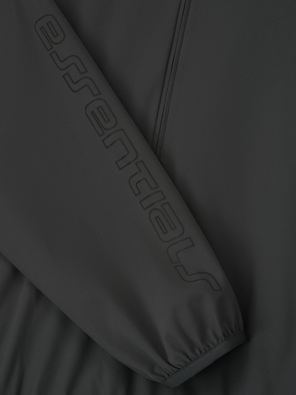 Close-up of iron grey Tech Nylon Half Zip Track Jacket sleeve featuring tonal embossed Essentials logo, gallery position 0