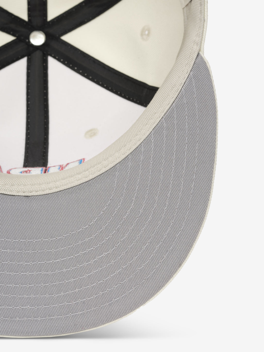 close-up of light gray cap brim with off-white stitched edge and black interior seams on snapback hat