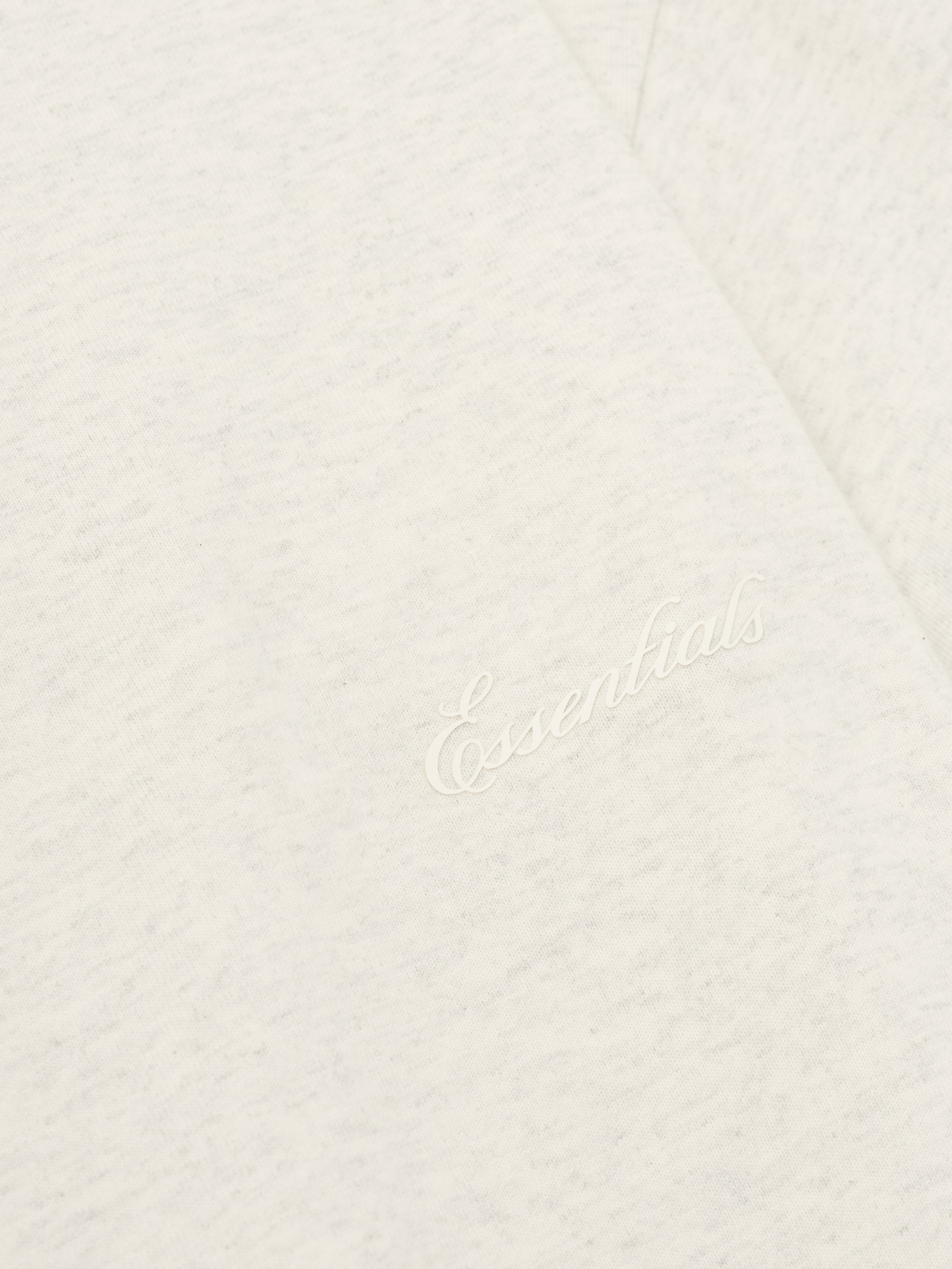 Close-up of oatmeal heather Kids Classic Short Sleeve Tee with discreet white embroidered Essentials logo on chest, gallery 0