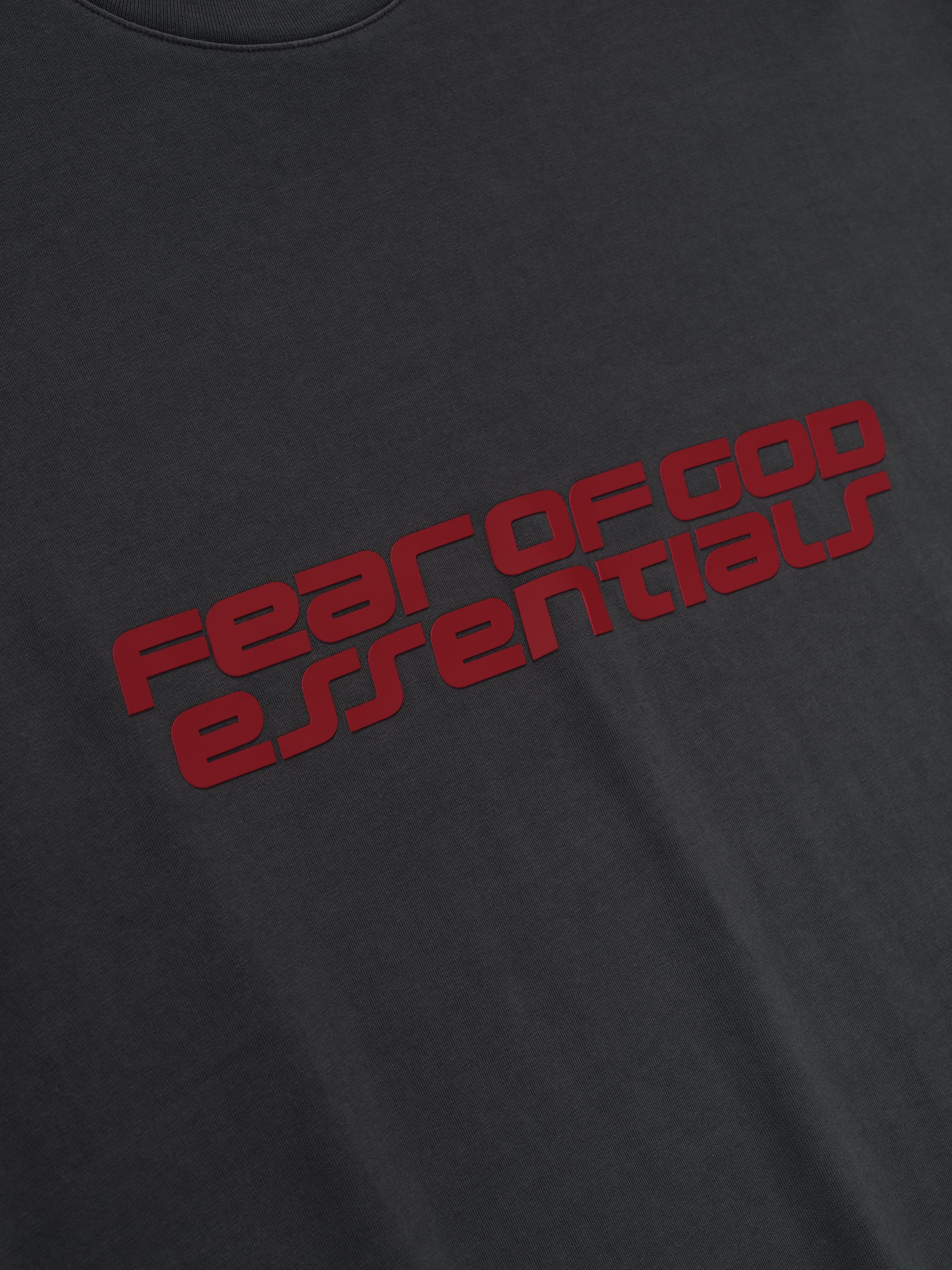 Close-up of iron grey Kids Classic Short Sleeve Tee with bold red Fear of God Essentials logo angled across chest, gallery 0