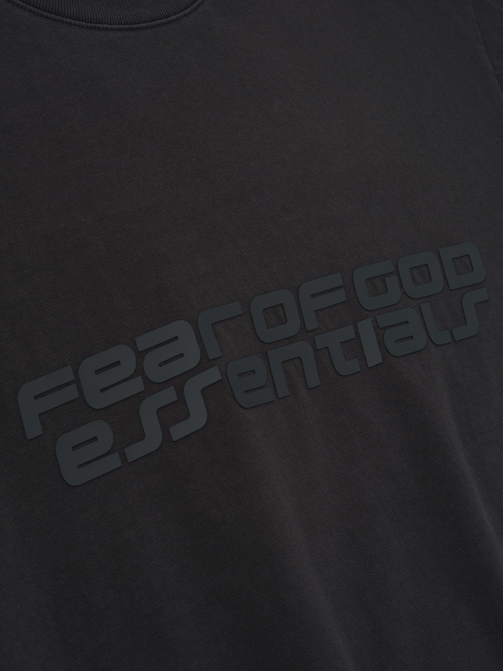 Close-up of vintage black Kids Classic Short Sleeve Tee showing embossed Fear of God Essentials logo across chest, gallery position 0
