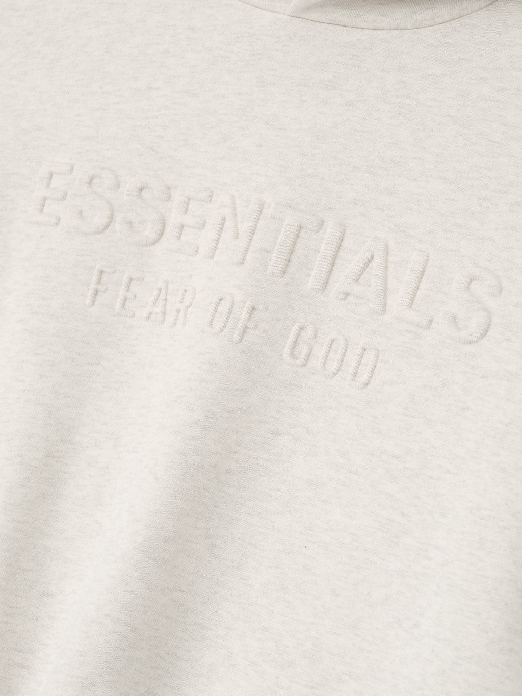 Close-up of oatmeal heather Kids Embossed Classic Hoodie showing raised ESSENTIALS Fear of God text on chest, gallery position 0
