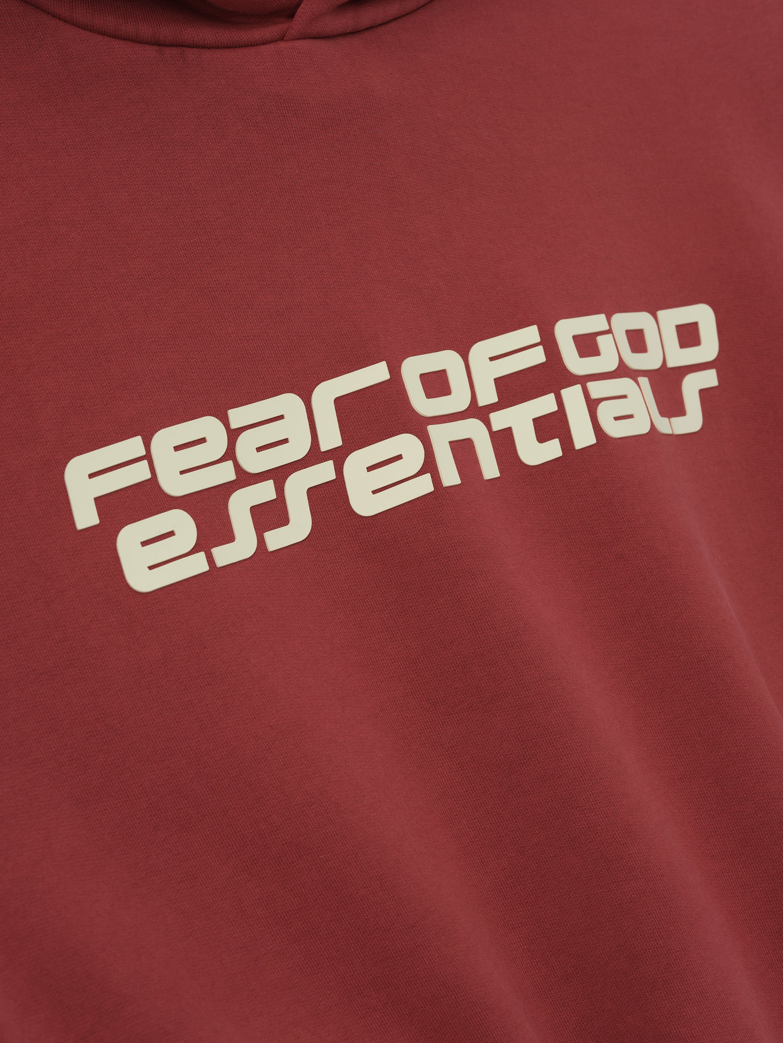 Close-up of crimson Kids Classic Hoodie showing angled Fear of God Essentials logo on chest, gallery position 0