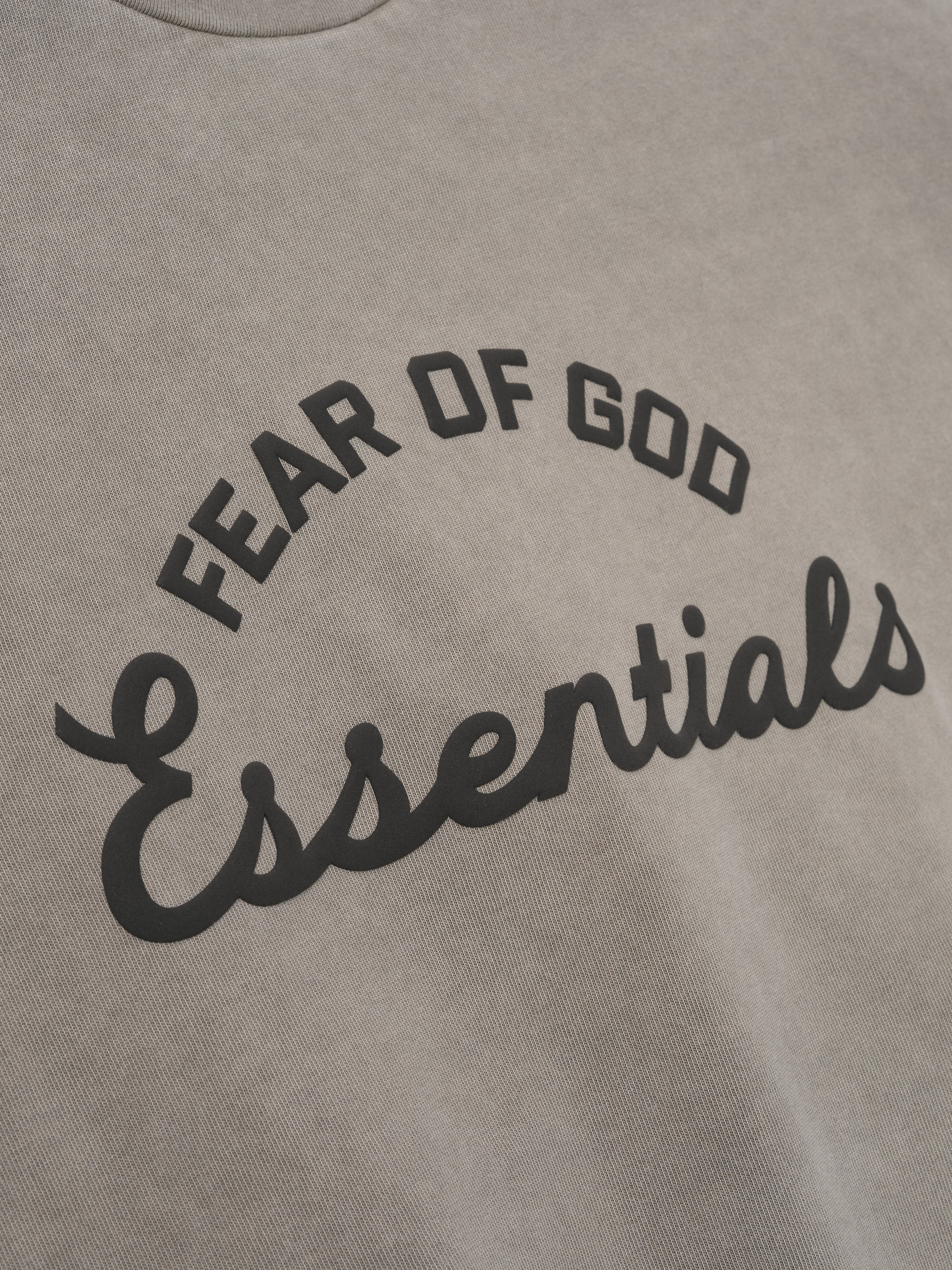 close-up of pigment-dyed heavyweight cotton tee fabric with curved Fear of God Essentials print in black