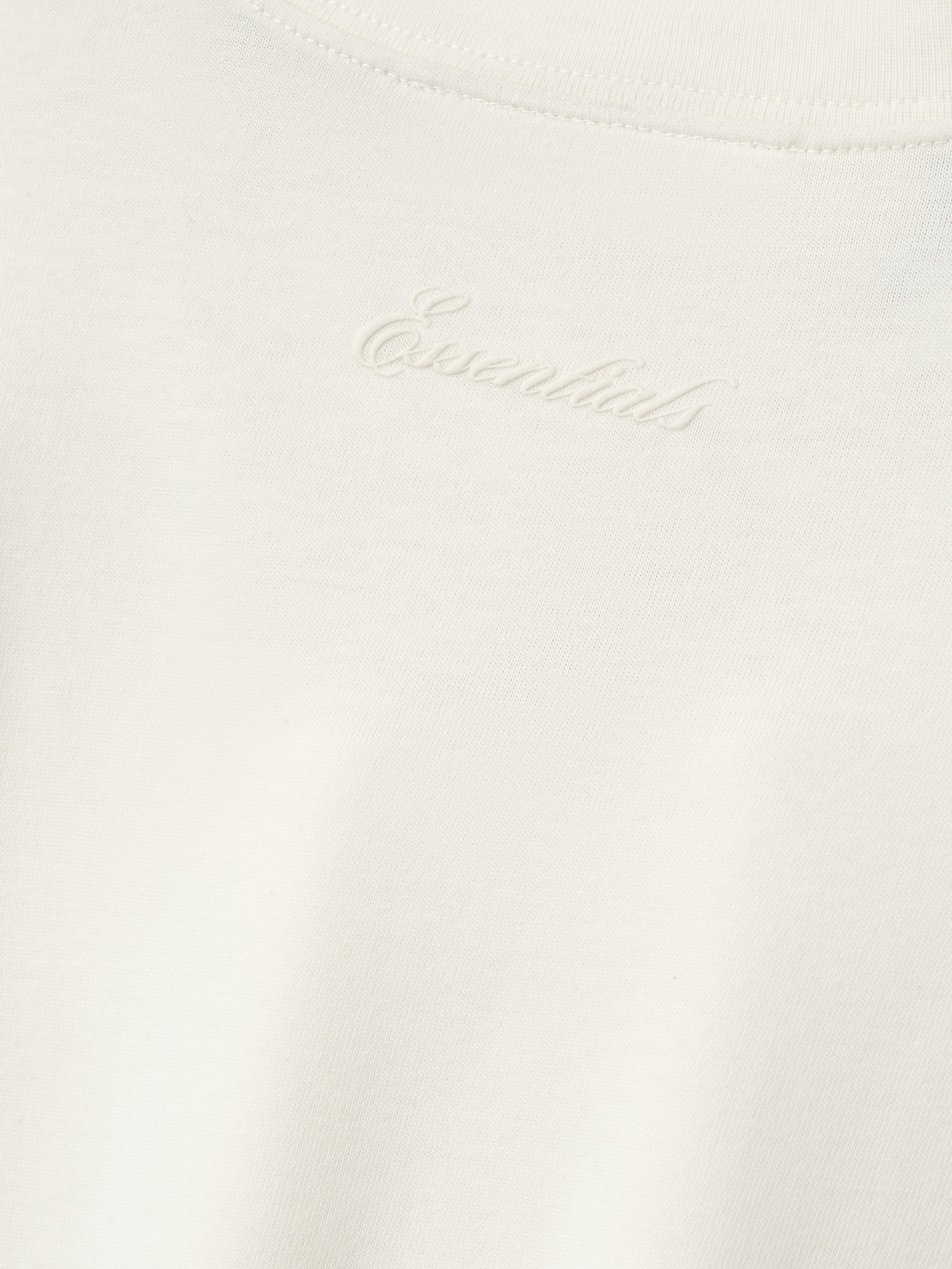 close-up of off-white cotton blend jersey fabric with subtle puff-printed Essentials logo at back neckline