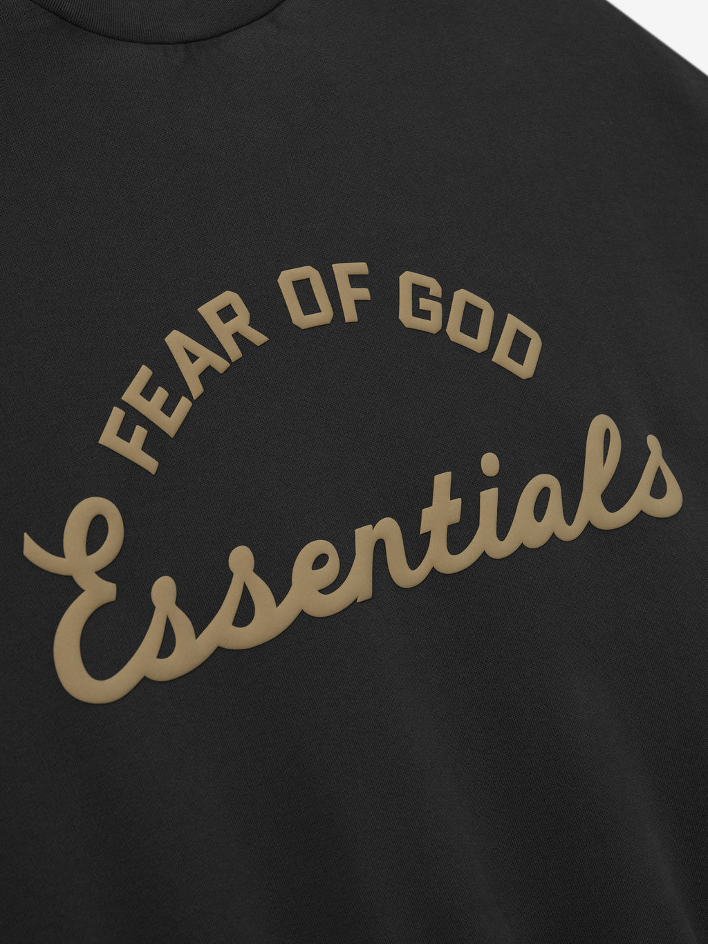 close-up of black kids crewneck sweatshirt with Fear of God Essentials training logo puff-printed in tan on front