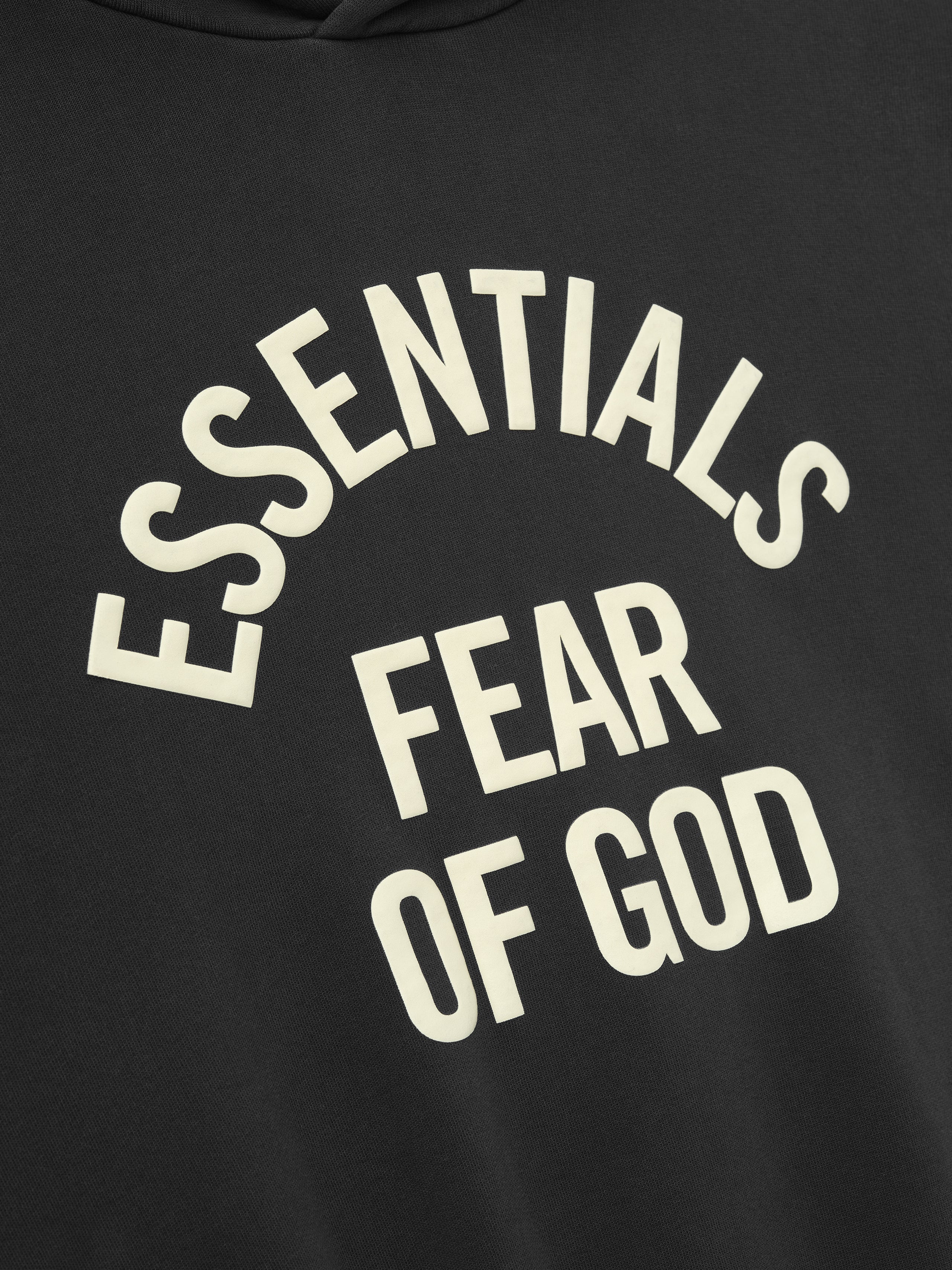 close-up of pigment-dyed black hoodie with off-white Essentials Fear of God text printed in arched style