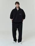 Front view of model wearing black Sporty Nylon Half Zip with matching pants and white slides on plain background