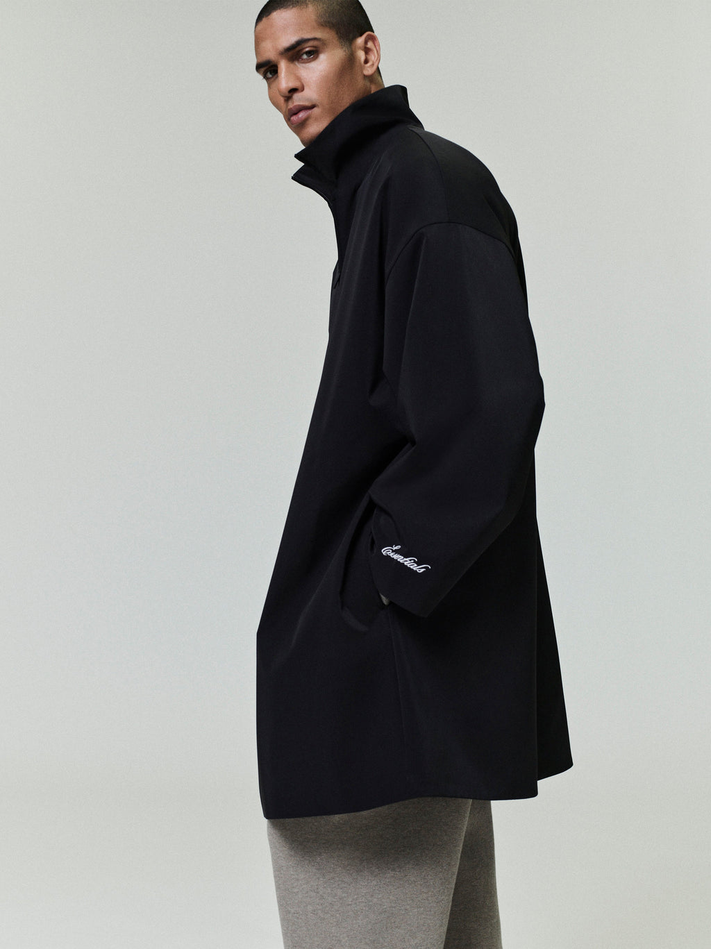 Model wearing black sporty nylon high neck jacket with subtle embroidery on cuff against plain background