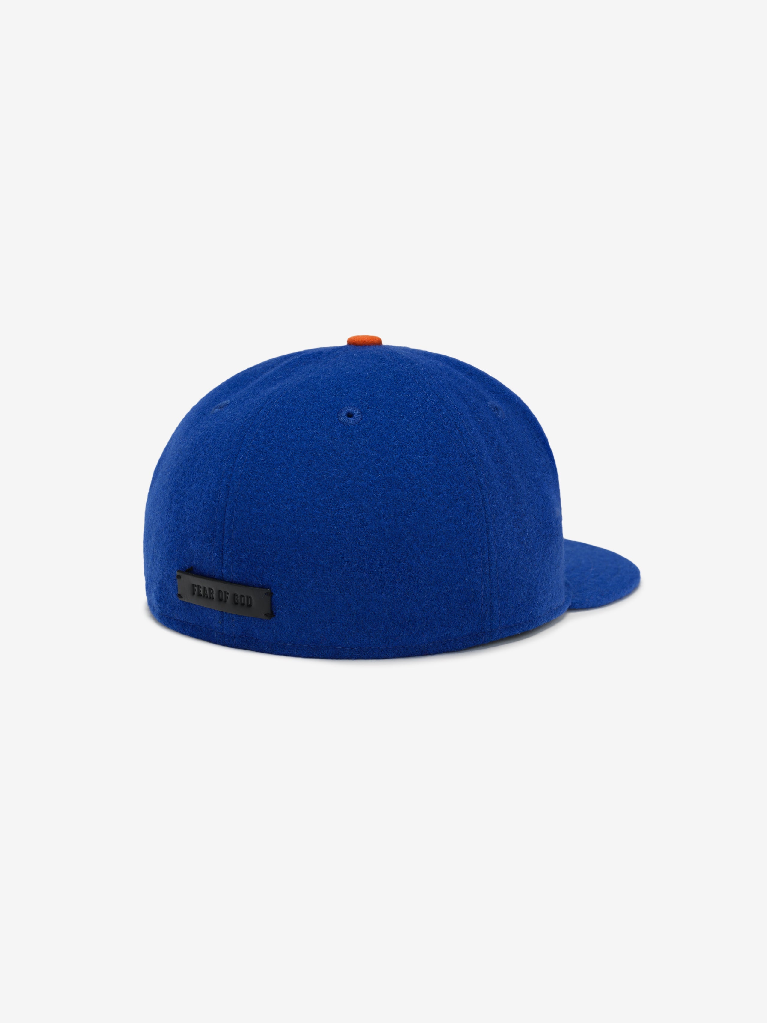 Rear side view of royal blue New York Mets Wool Retro Crown 59FIFTY fitted cap with black Fear of God tag and orange button detail