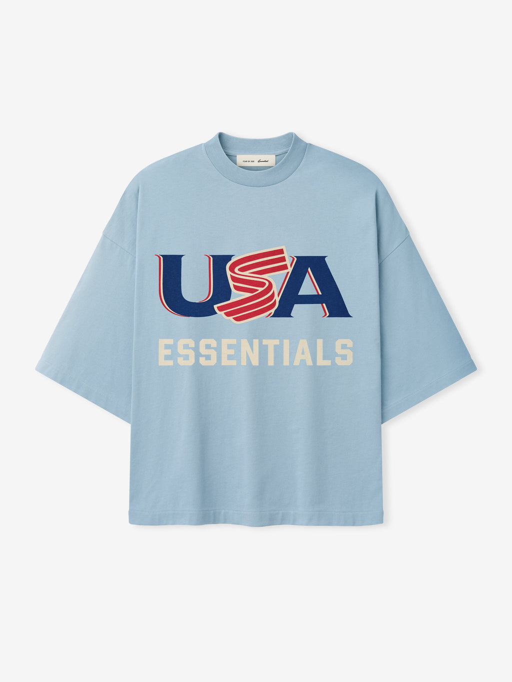 Light blue oversized short-sleeve T-shirt with bold red, white, and blue "USA" and cream "ESSENTIALS" text on front center