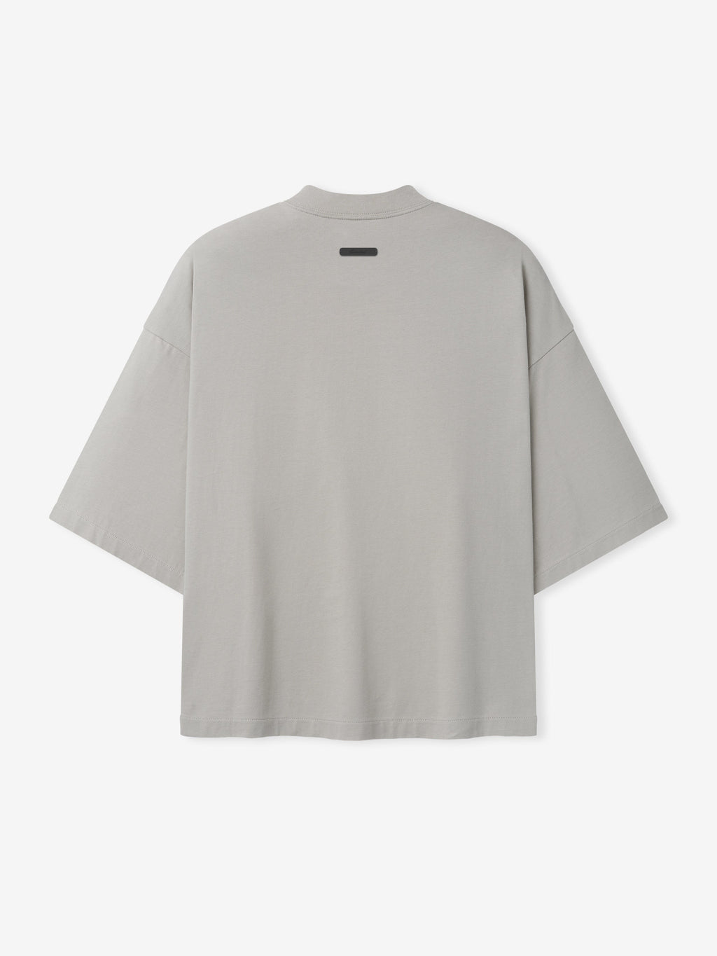 Back view of oversized light gray short-sleeve shirt with dropped shoulders and small black label near neckline
