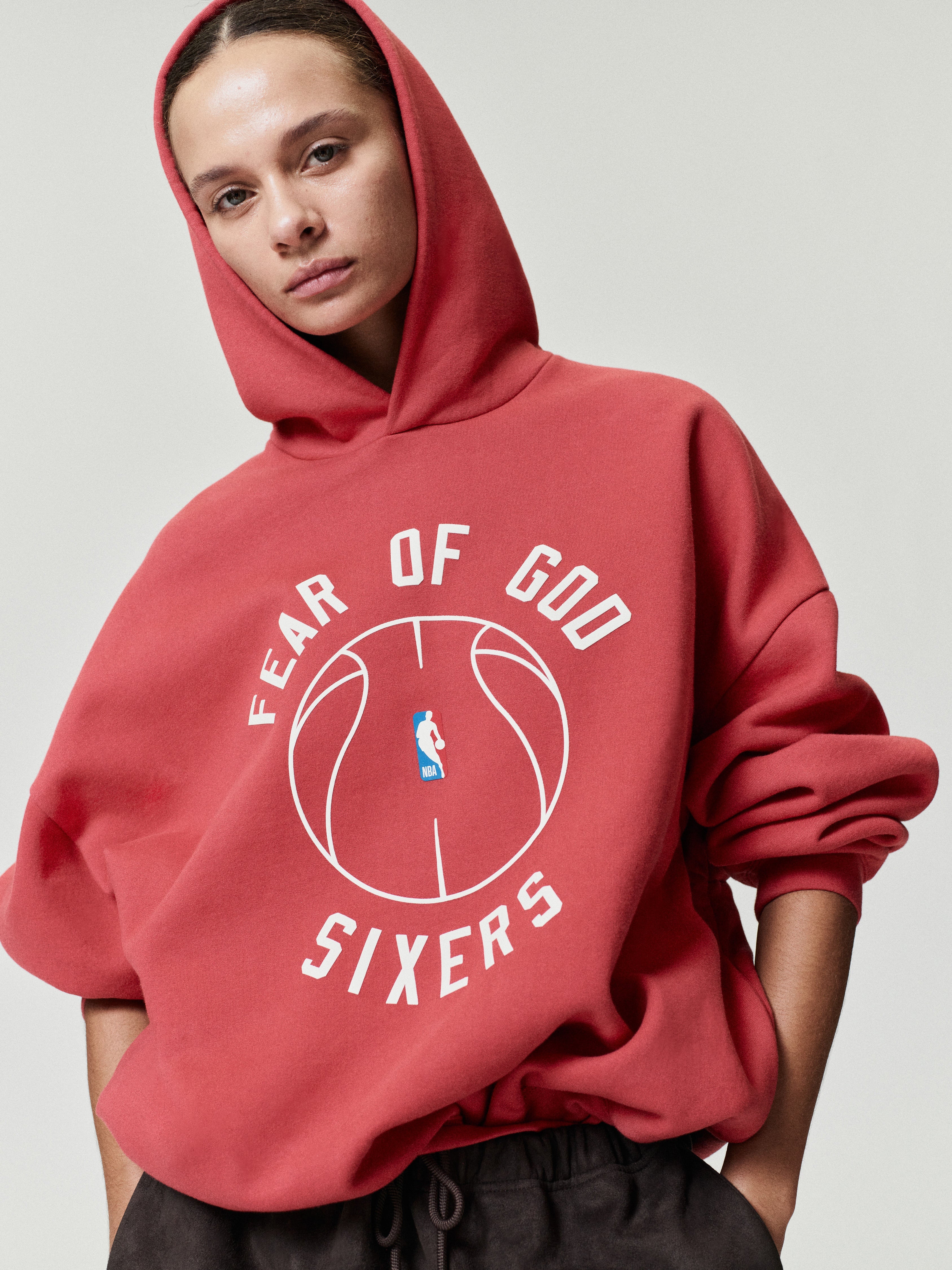 red heavyweight cotton fleece hoodie with white Fear of God Sixers text encircling NBA logo basketball outline on front center