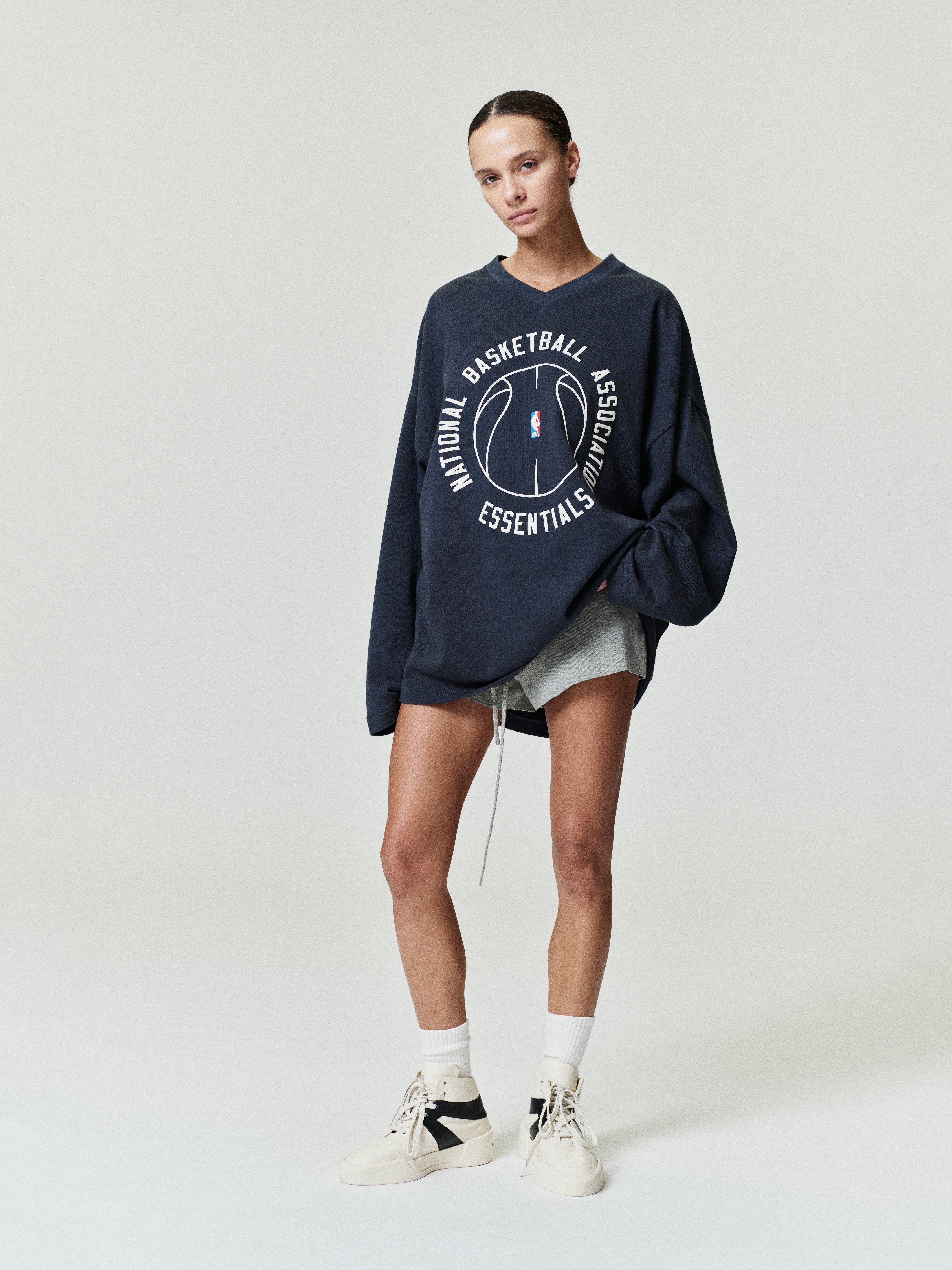 oversized navy cotton long sleeve V-neck tee with circular NBA Essentials basketball graphic center chest