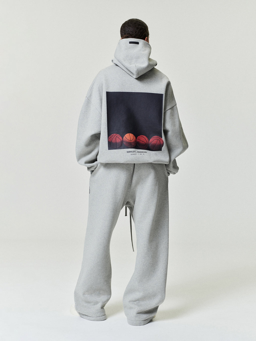 model wearing light gray heavyweight cotton fleece relaxed fit sweatpants with a loose silhouette and drawstring waist