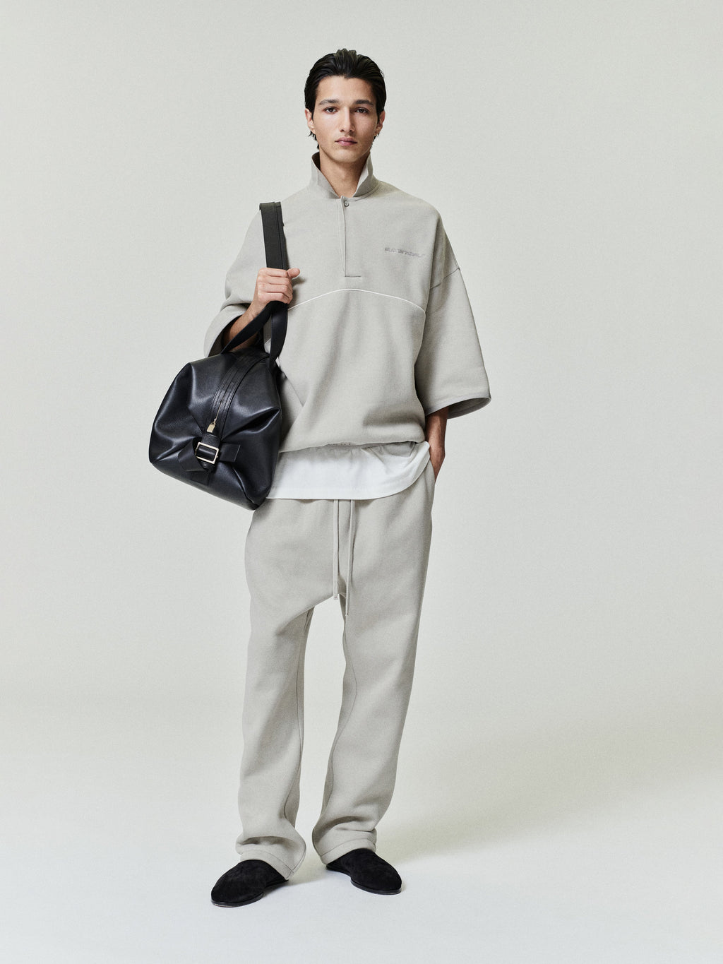 model wearing light beige relaxed fit sweatpants with drawstring waist and matching oversized quarter-zip pullover