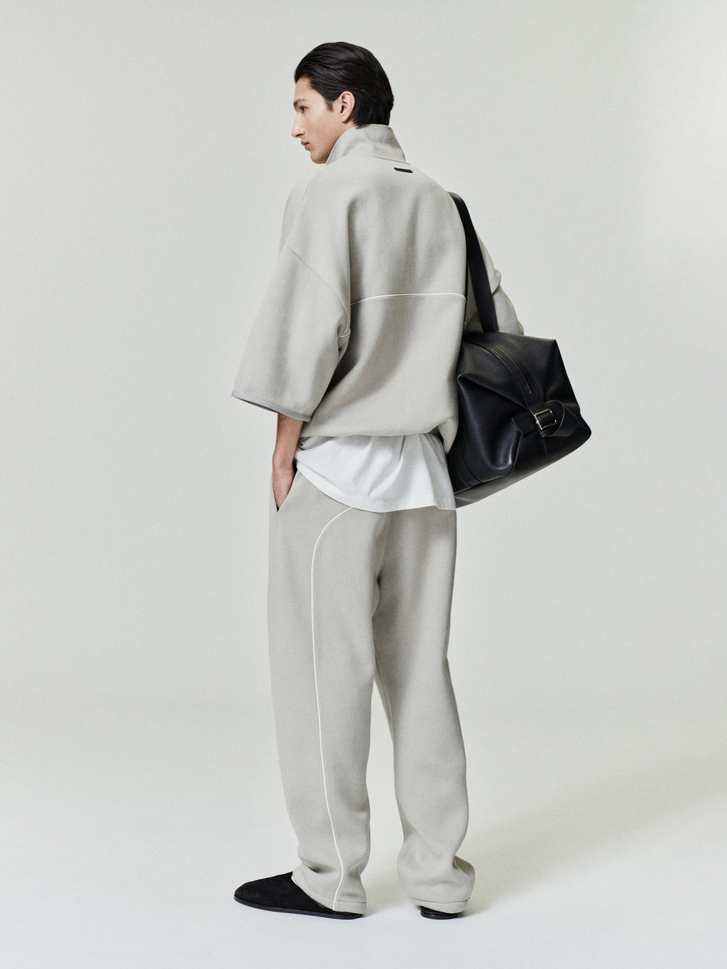 man wearing light grey baggy sweatpants with white sportswear piping and relaxed fit paired with matching top