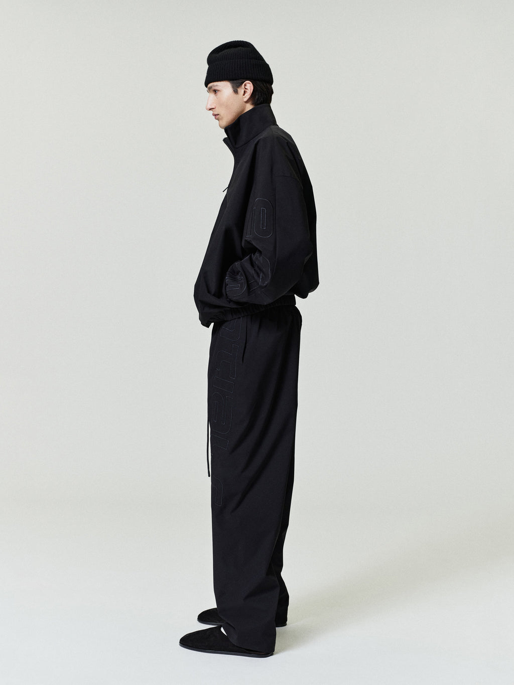 Person wearing a black outfit with a beanie on a white background