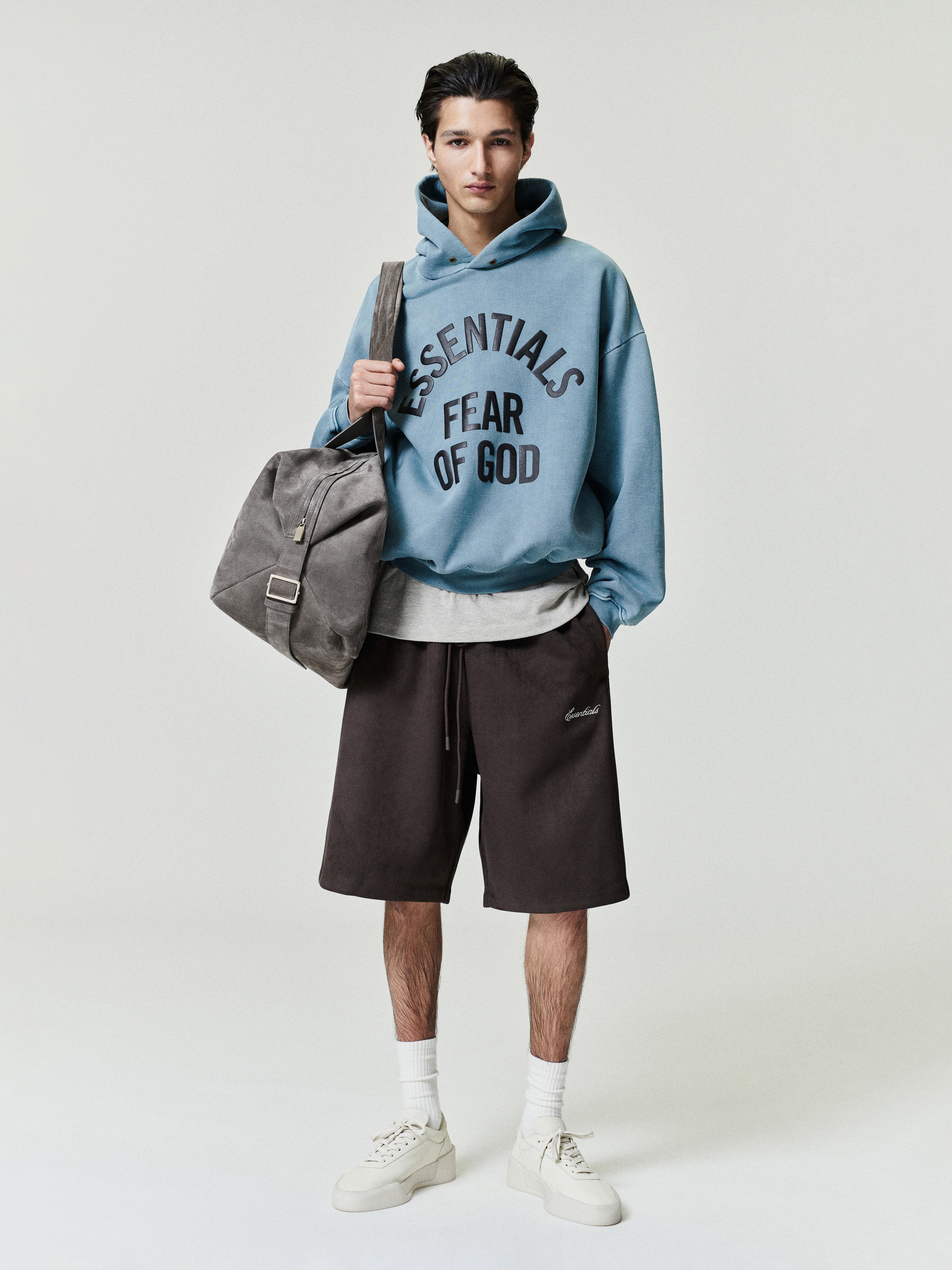 front view of pigment-dyed blue cropped heavyweight fleece hoodie with large black Essentials Fear of God print