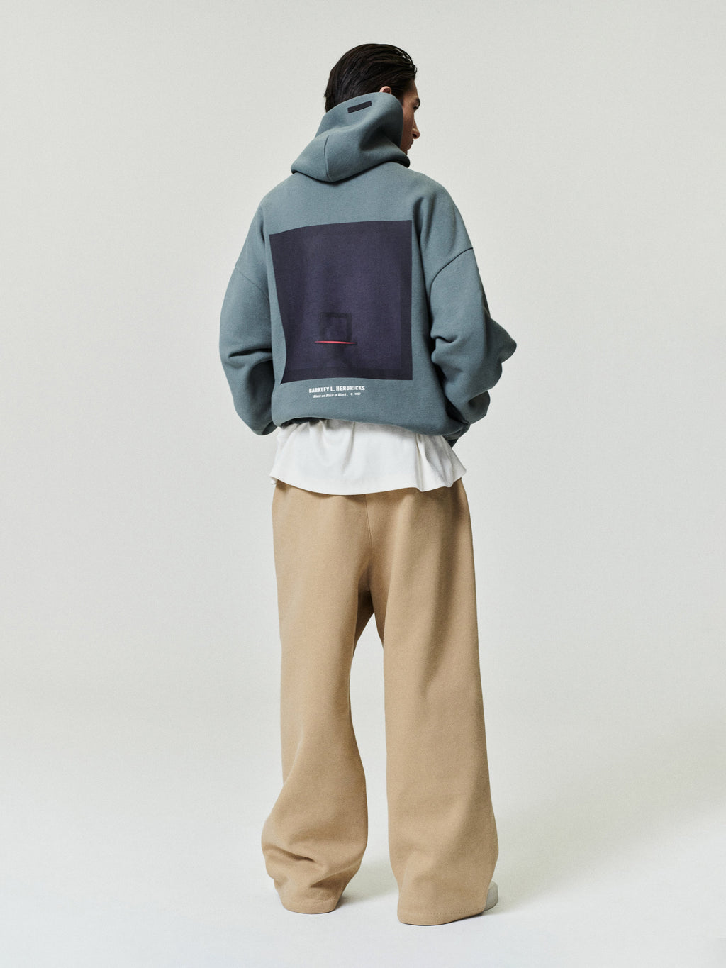 muted blue oversized hoodie with large square graphic and Barkley Hendricks text on back worn by model facing away