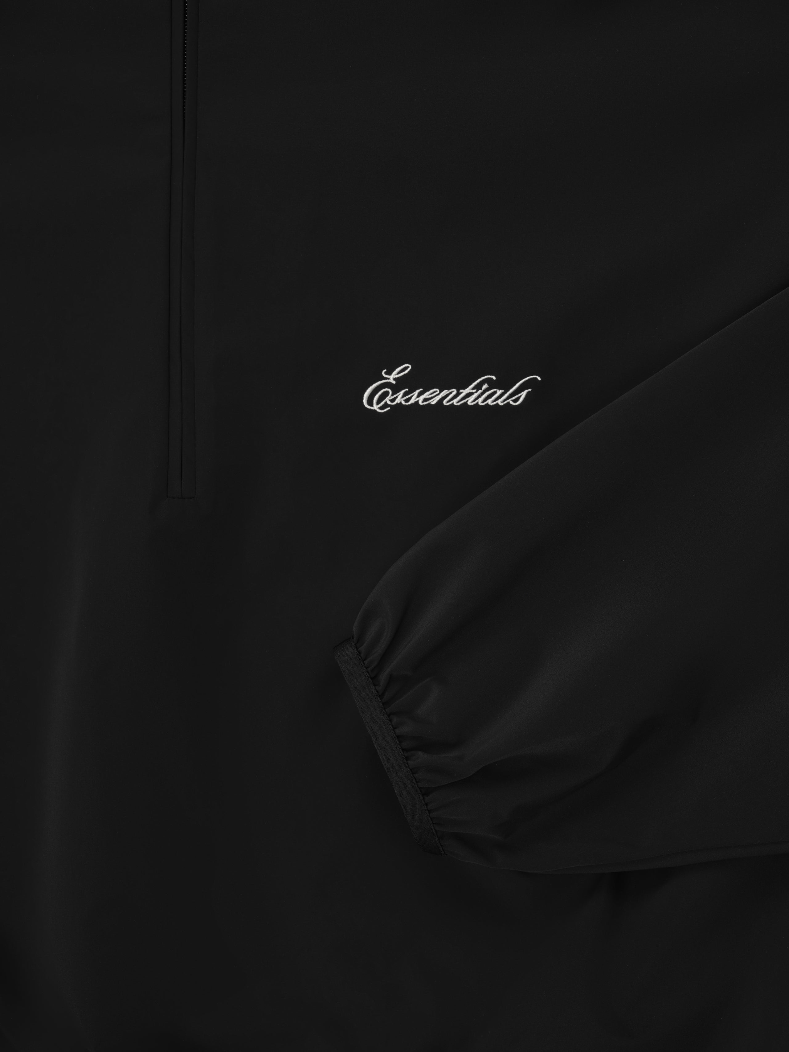 Close-up of black Sporty Nylon Half Zip focusing on sleeve cuff and white Essentials logo embroidery
