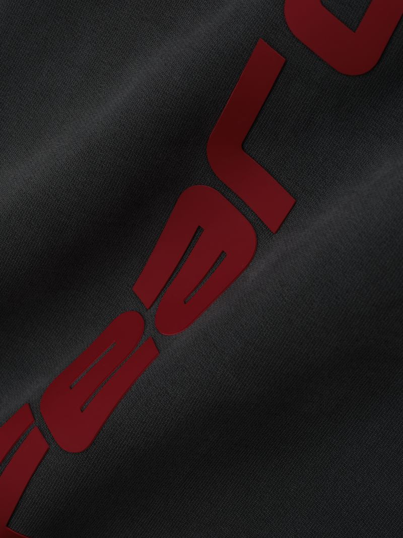 Close-up of black Heavy Fleece Flare Sweatpant fabric highlighting bold red embossed vertical lettering, gallery image 0, file ok2JV2uA.jpg